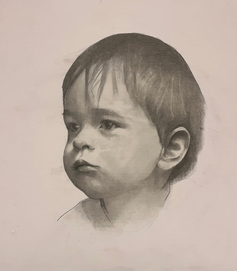 A realistic pencil drawing of a young child with short hair, gazing slightly to the left. The portrait captures soft facial features and a calm expression on a plain, light background.